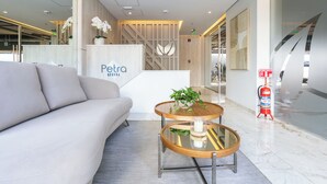 A modern lobby with a reception desk labeled "Petra", a sofa, and a glass coffee table with a plant. - Sky Stays at Life Mariscal (Asunción)
