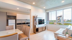 A modern apartment with a dining area, kitchen, living room, and large windows offering a city view. - Sky Stays at Life Mariscal (Asunción)