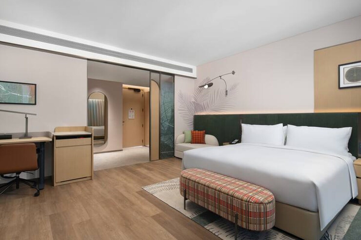 Una habitación de hotel moderna con una cama grande, un escritorio y un espacio para sentarse.