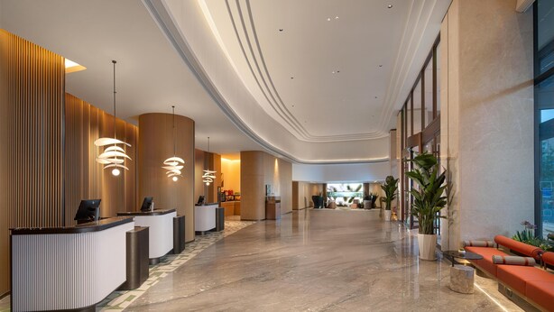 Un rebedor modern d'hotel amb taulell de recepció, zona de seients i grans finestres.