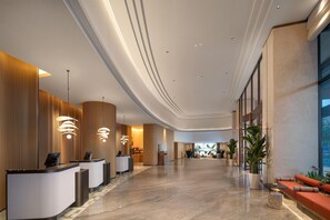 En moderne hotellobby med receptionsdisk, siddeområde og store vinduer.