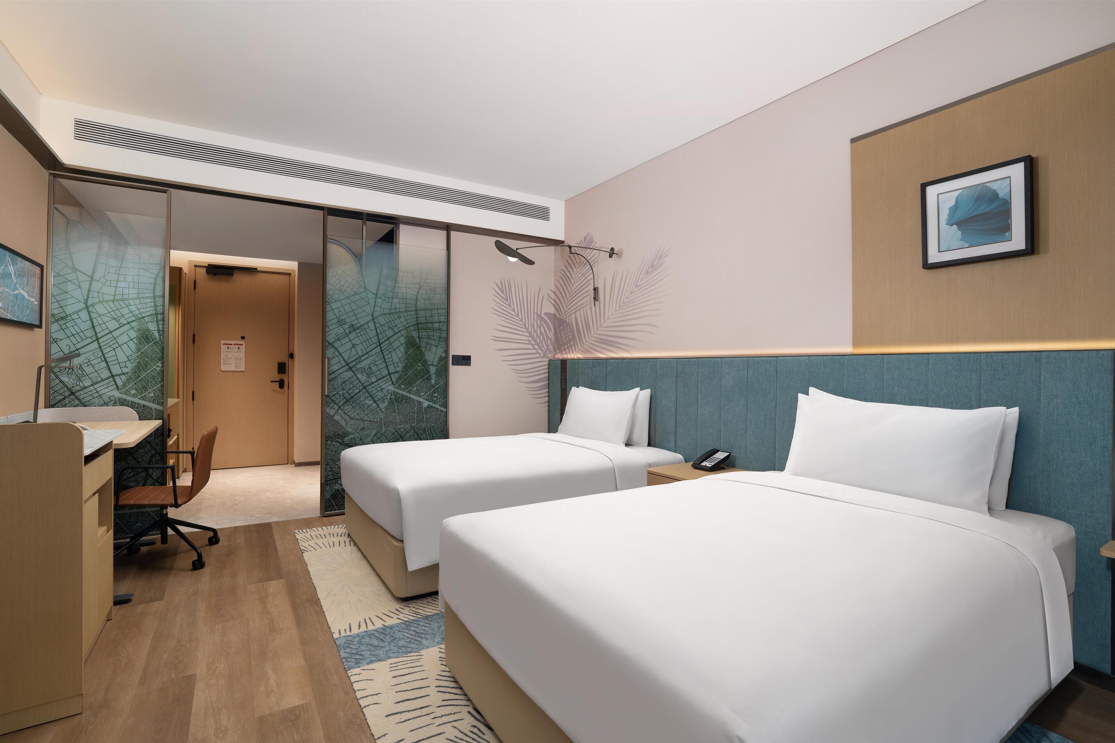 Habitación de hotel con dos camas, un escritorio y una silla.
