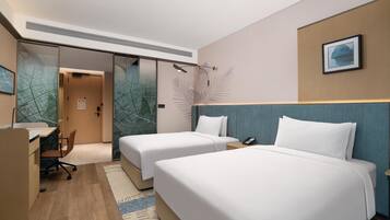 Quarto de hotel com duas camas, uma mesa e uma cadeira.