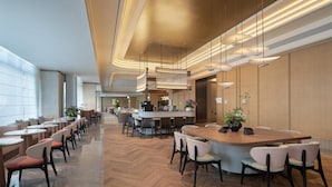 Un restaurant modern amb una barra llarga, diverses zones d'assaient i un disseny de sostre càlid.