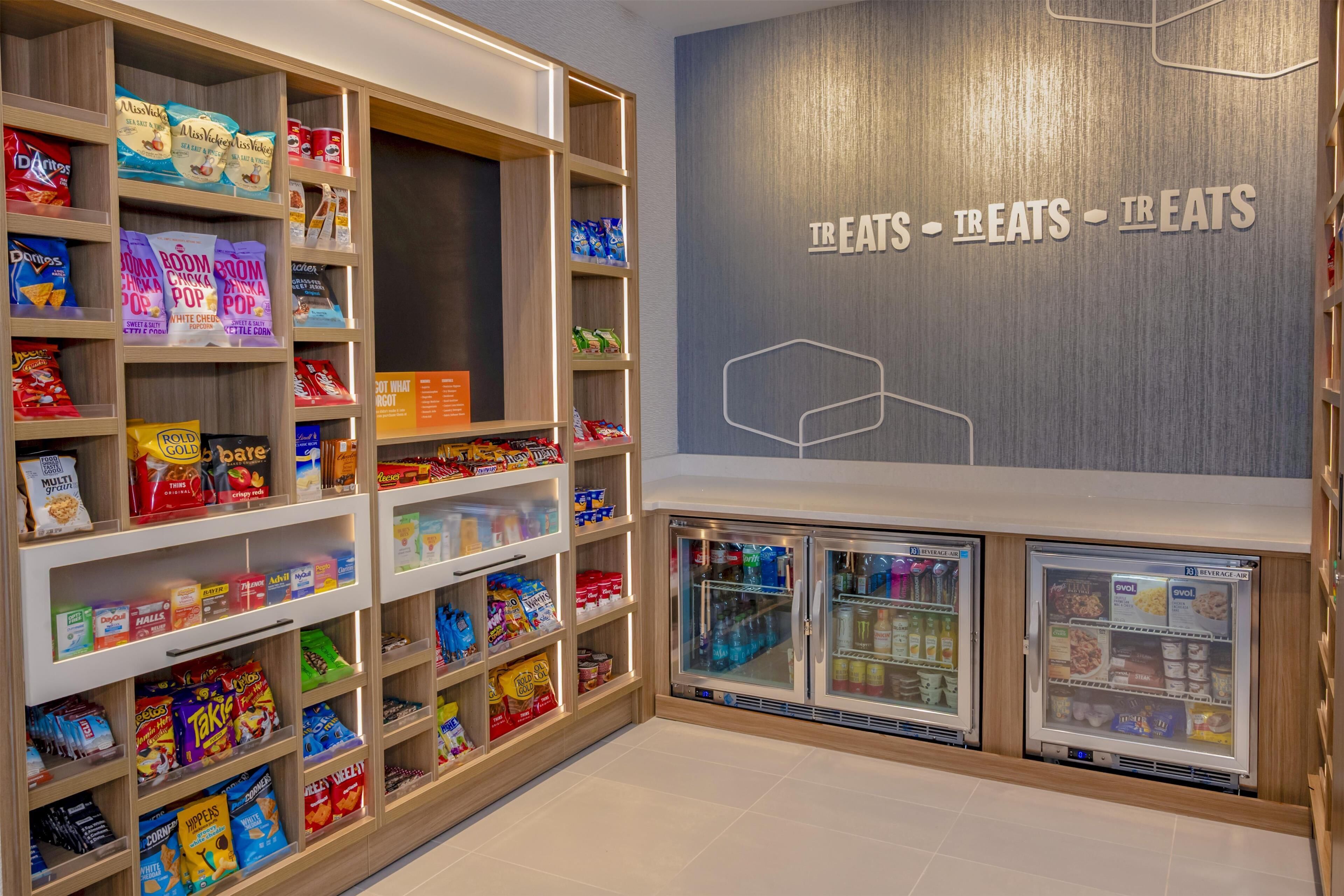 A snack and beverage section with shelves stocked with various snacks and drinks, and two refrigerated display cases.