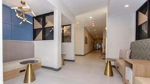 A modern hotel lobby with a seating area, a reception desk, and a hallway leading to the exit. - Hampton Inn & Suites Irving Hwy 183 (Irving)