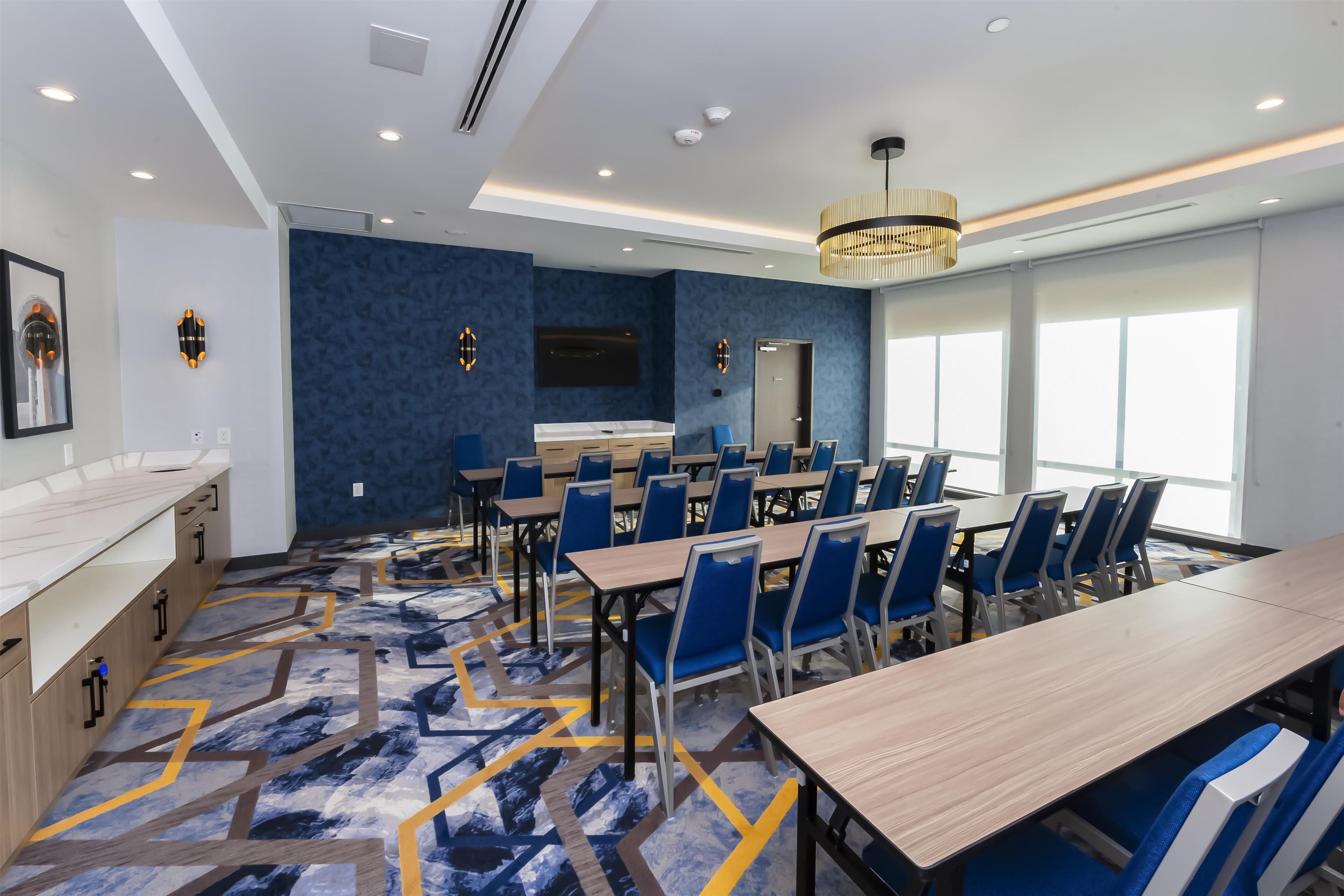 Un salón de conferencias con una larga mesa, sillas azules y una alfombra estampada.