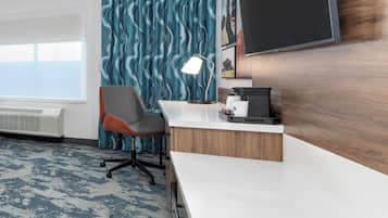 A modern office space with a white desk, a grey office chair, a large flat-screen TV, and a patterned wall.