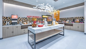 A modern breakfast area with a counter displaying various food items and a coffee machine. - Hampton Inn & Suites Irving Hwy 183 (Irving)