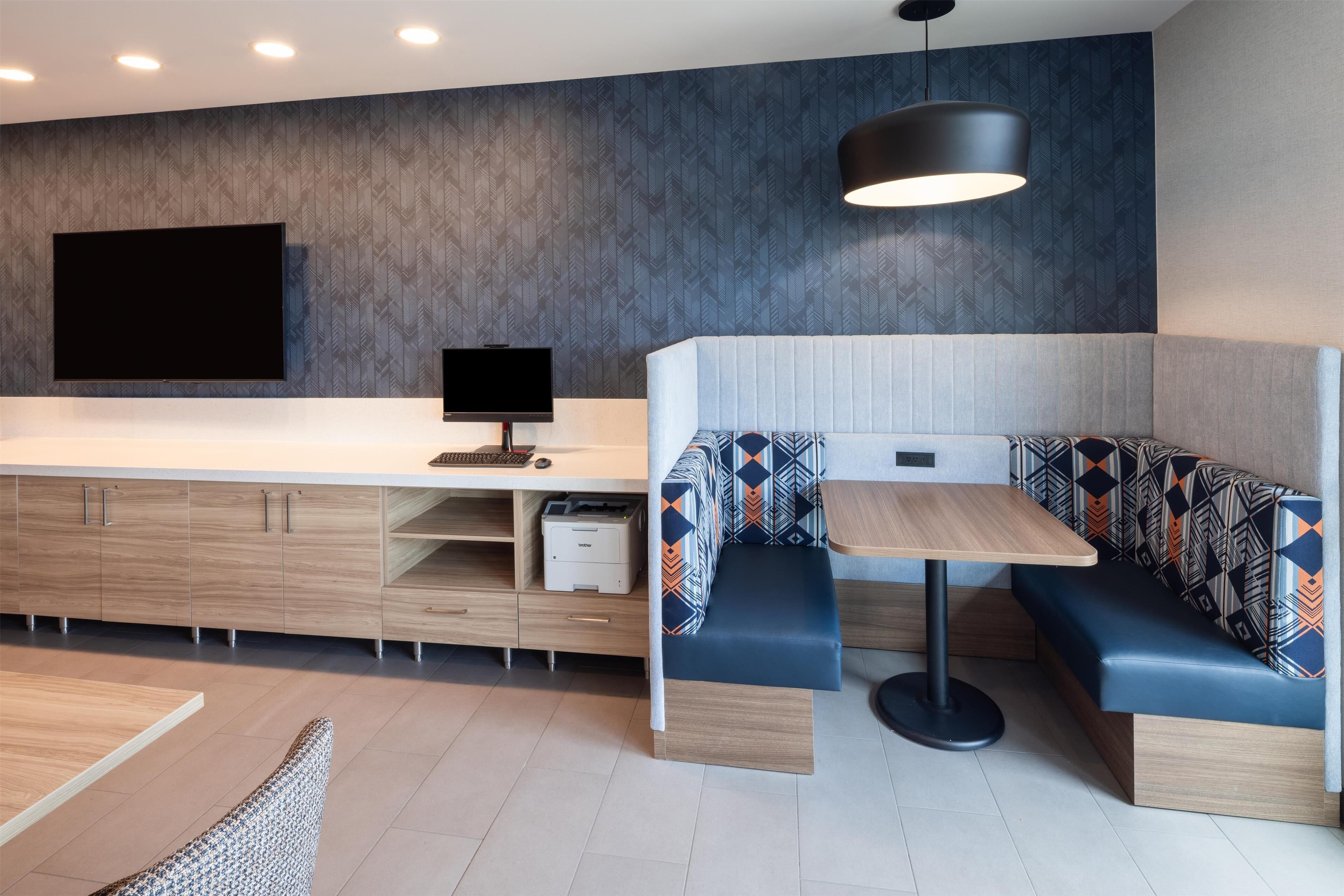 Un espacio habitable moderno y compacto, con cocina integrada, zona de estar con mesa y televisor de pantalla plana montado en la pared.