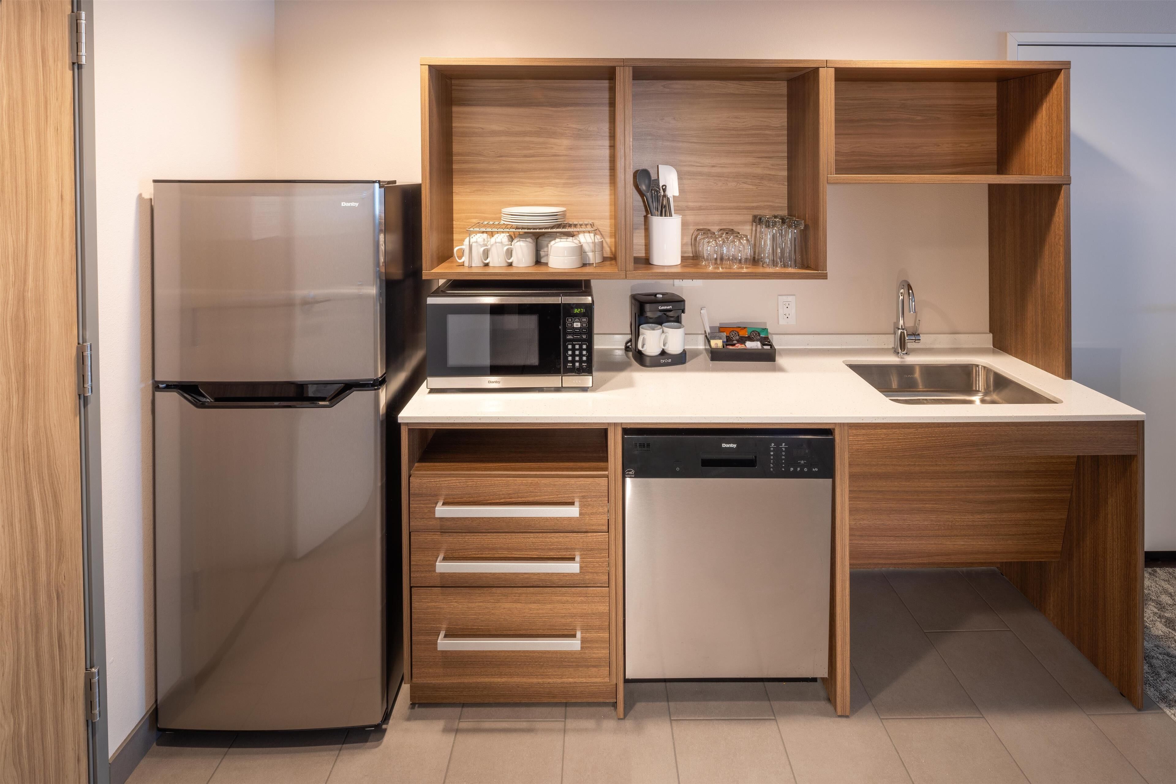 A modern kitchen with a refrigerator, microwave, coffee maker, and dishwasher.