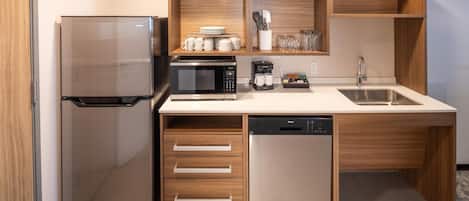 A modern kitchen with a refrigerator, microwave, coffee maker, and dishwasher.