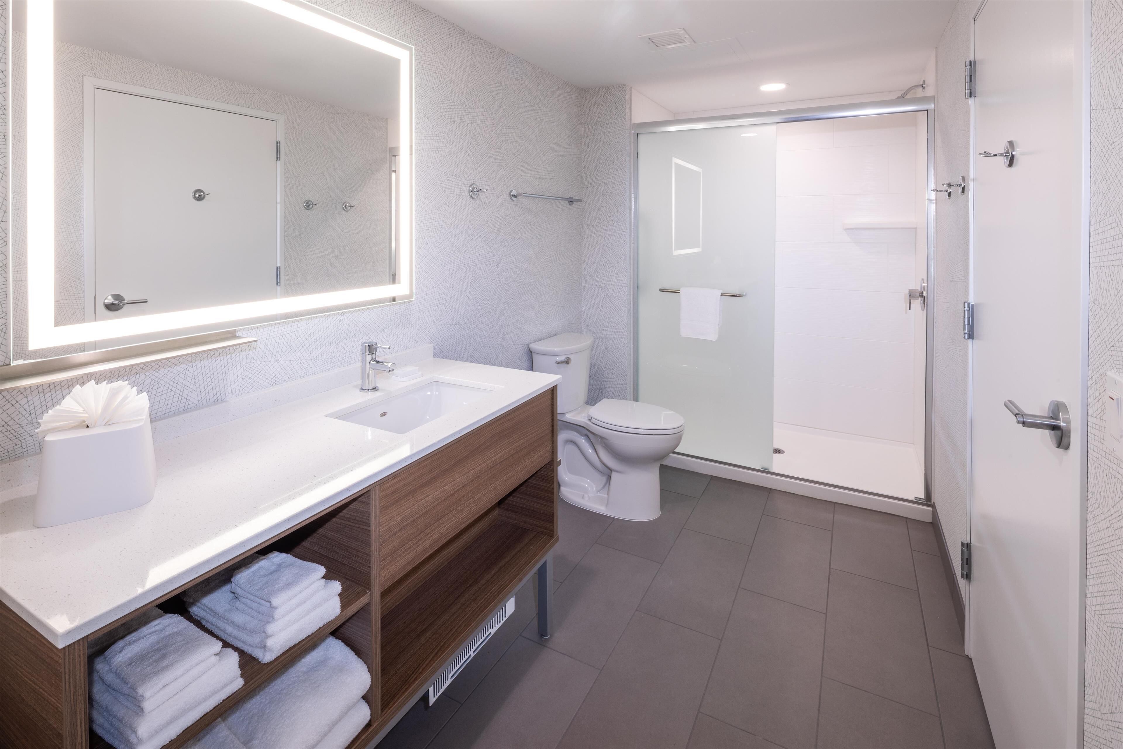 A modern bathroom with a double sink, a toilet, and a glass-enclosed shower.