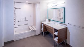 A modern bathroom with a bathtub, shower, vanity, and a large mirror.