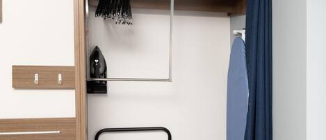 Una habitación compacta con un armario de madera, un escurridor de metal con utensilios y una cortina azul.