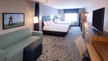 Habitación de hotel con dos camas, un sofá, un televisor y un escritorio.