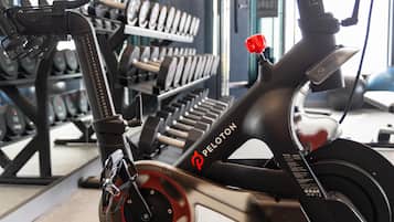 Een Peloton hometrainer in een sportschool, met krachttrainingsapparatuur op de achtergrond.