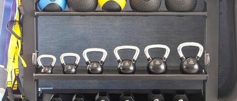A storage unit with various weights and kettlebells.