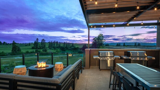 Eine Terrasse im Freien mit Feuerstelle, Sitzgelegenheiten und Grillstationen, mit Blick auf eine malerische Landschaft.