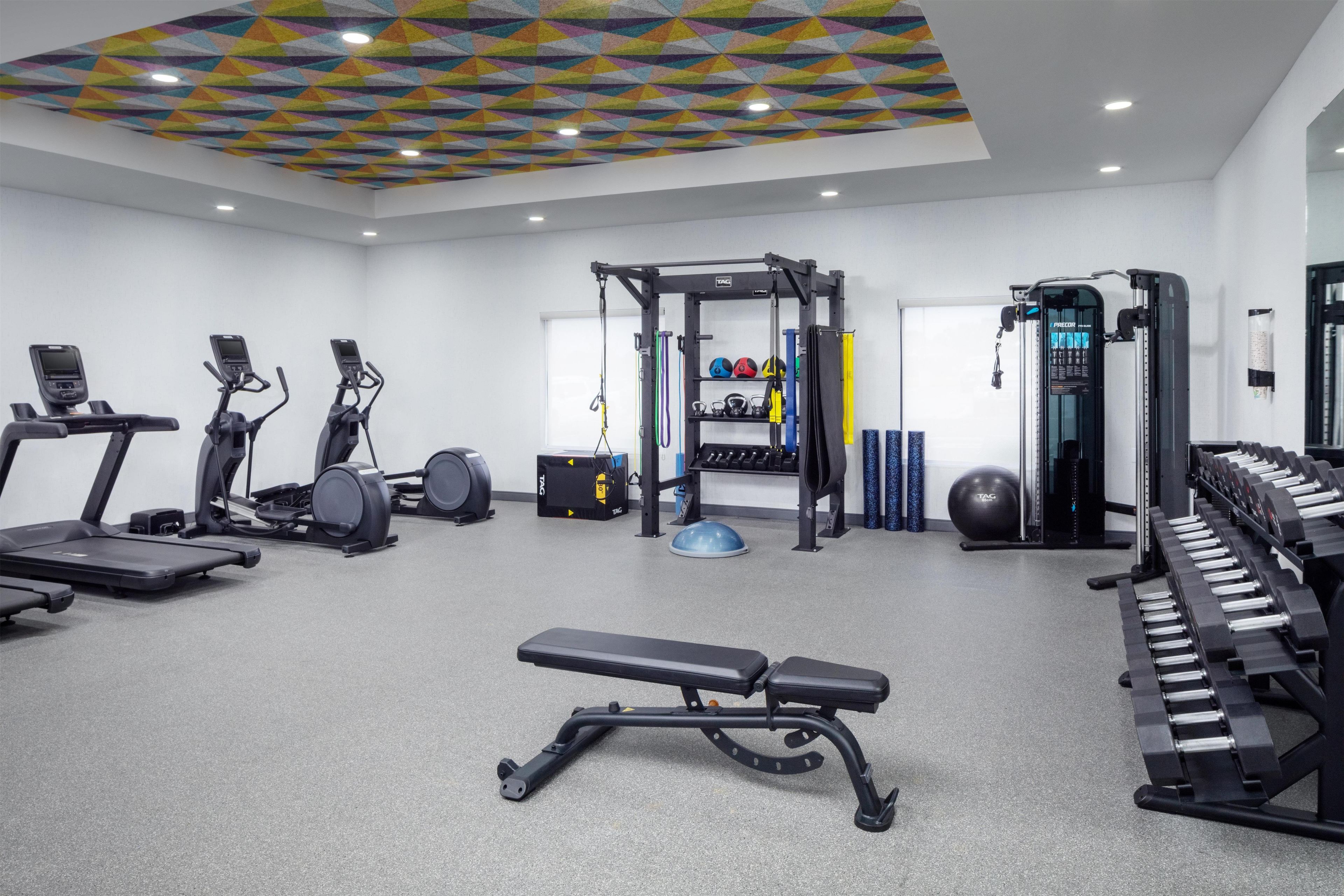 A gym with exercise equipment including treadmills, a bench, and a weightlifting station.