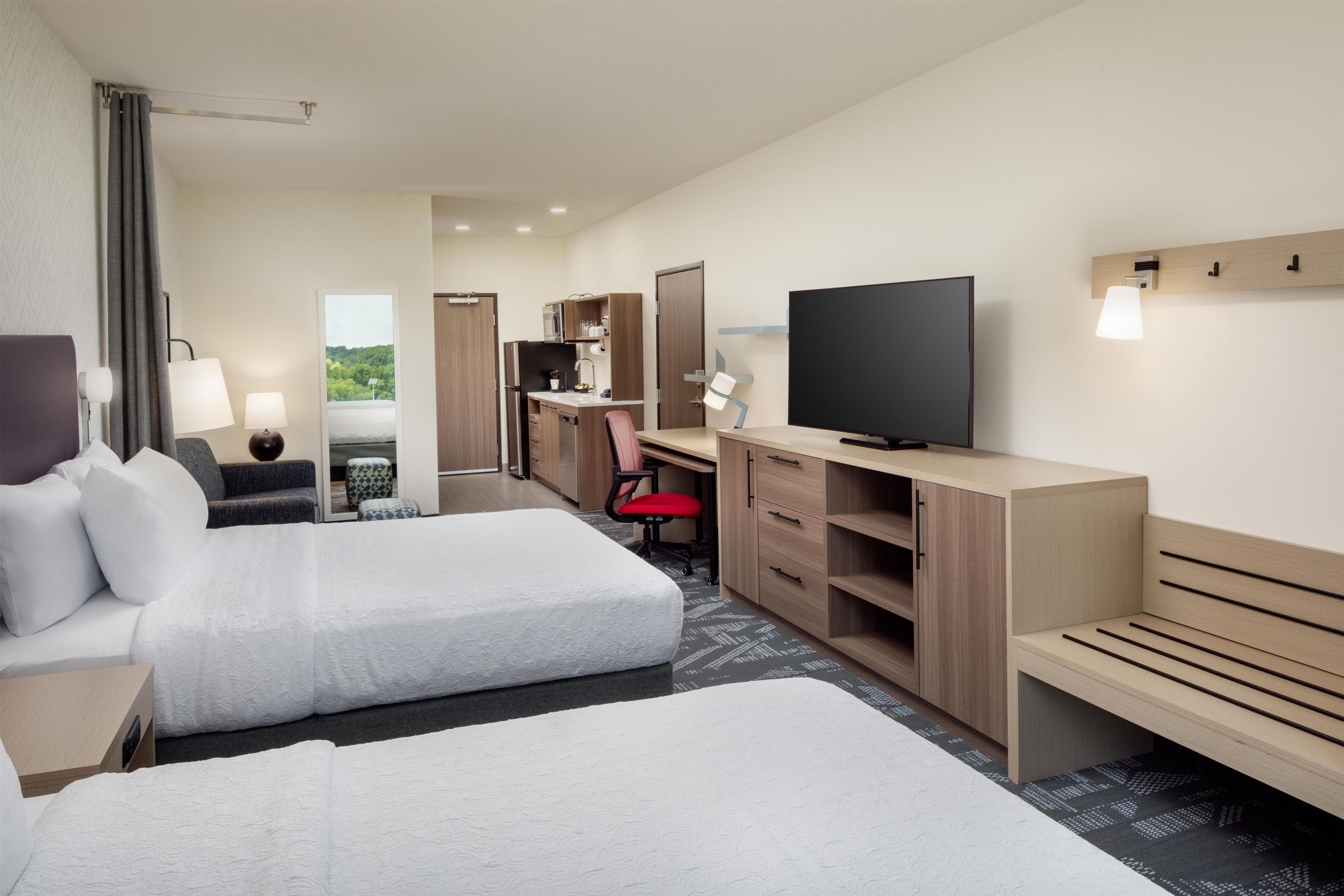 Une chambre d’hôtel avec deux lits, un bureau, une télévision et une vue sur l’extérieur.