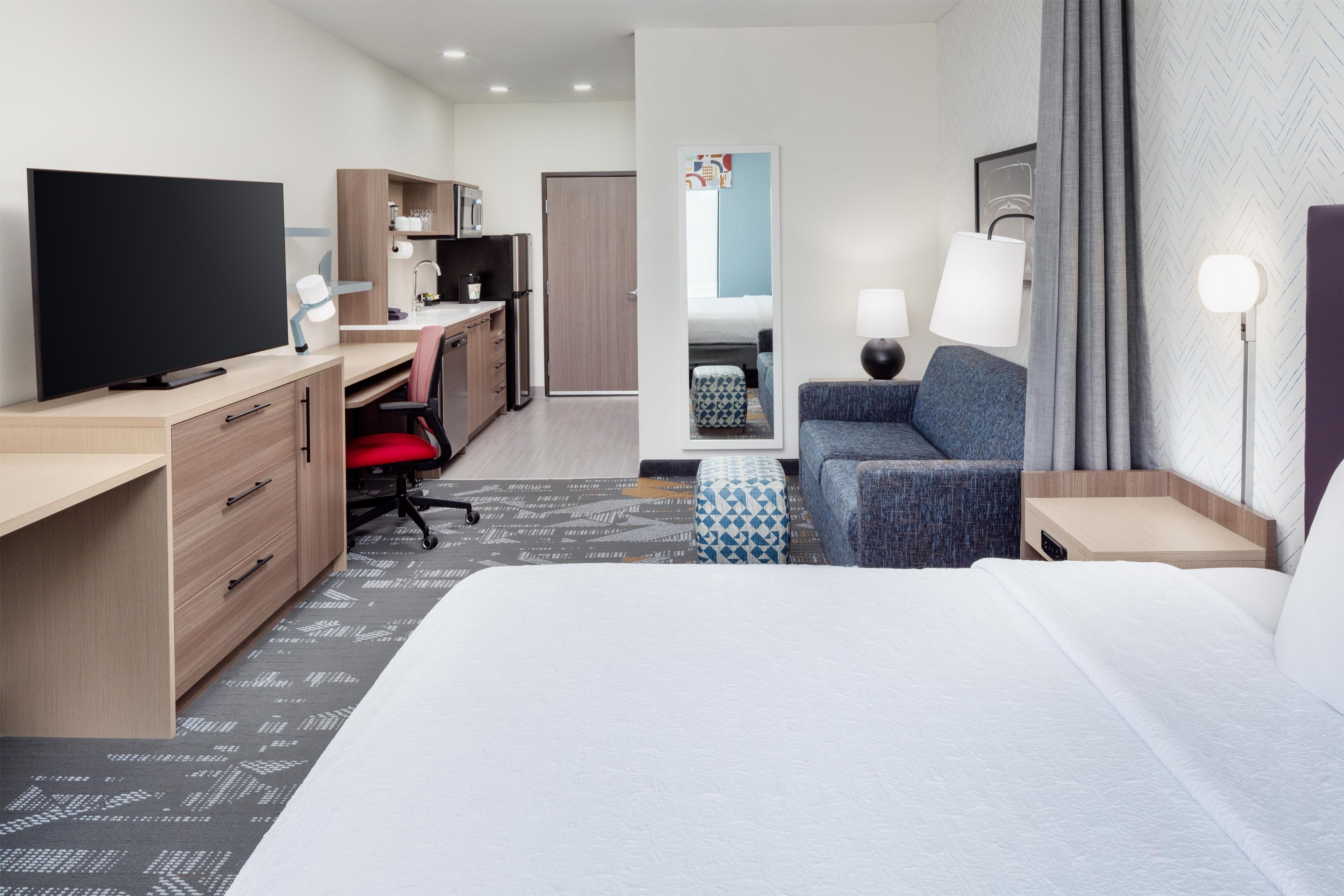 Une chambre d’hôtel équipée d’un lit, d’un bureau, d’une télévision, d’une chaise, d’un canapé et d’une lampe.
