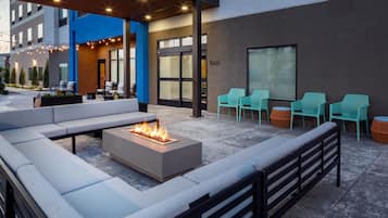 An outdoor seating area with a fire feature, a pool, and a view of the building.
