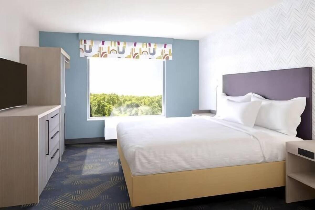 A hotel room with a bed, a television, a window with a view, and a desk.