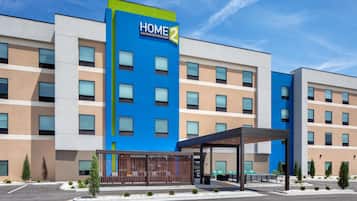 A modern hotel building with a prominent 'HOME 2' sign, multiple floors, and a covered entrance area.