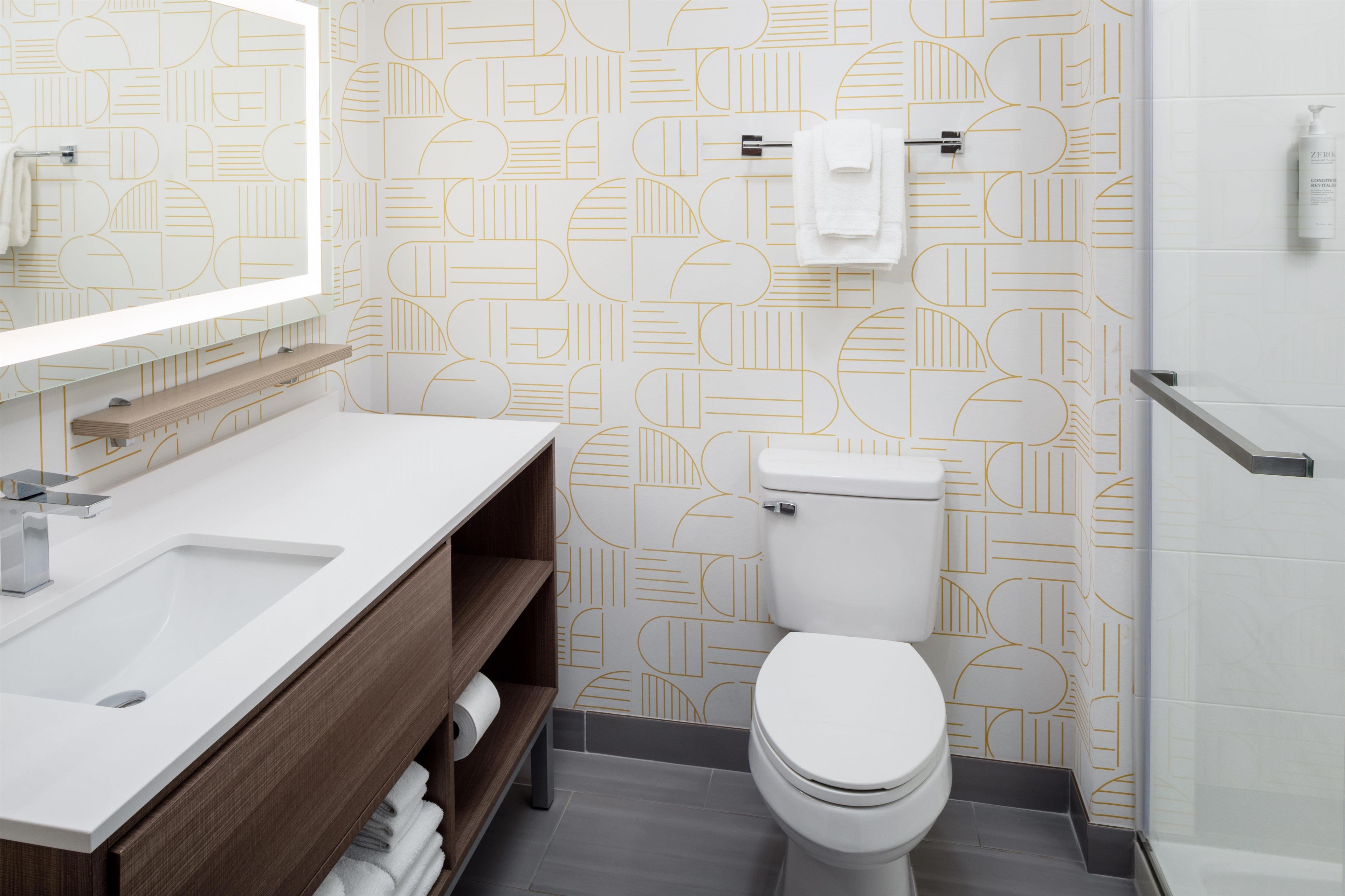 A modern bathroom with a white sink, wooden vanity, and a toilet.