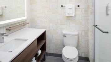 A modern bathroom with a white sink, wooden vanity, and a toilet.