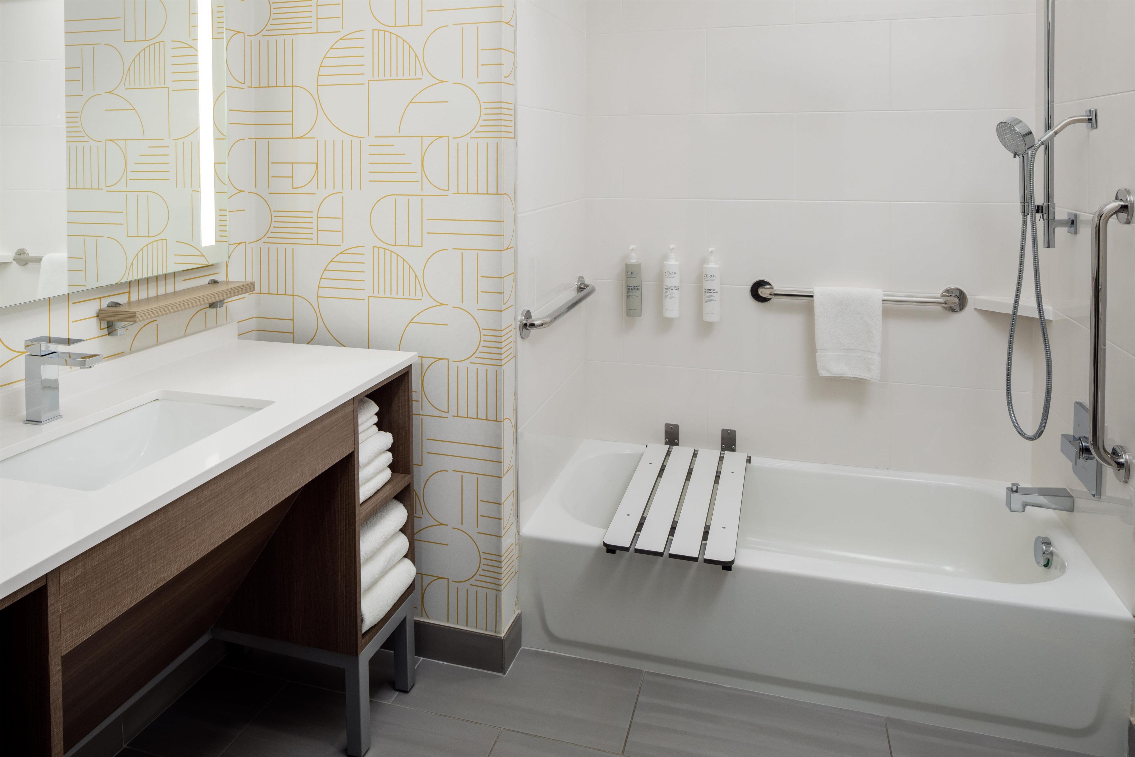 A modern bathroom with two sinks, a shower, and a towel rack.