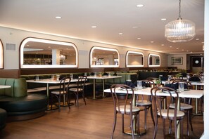 Un restaurante con cabinas y mesas, suelo de madera e iluminación colgante.