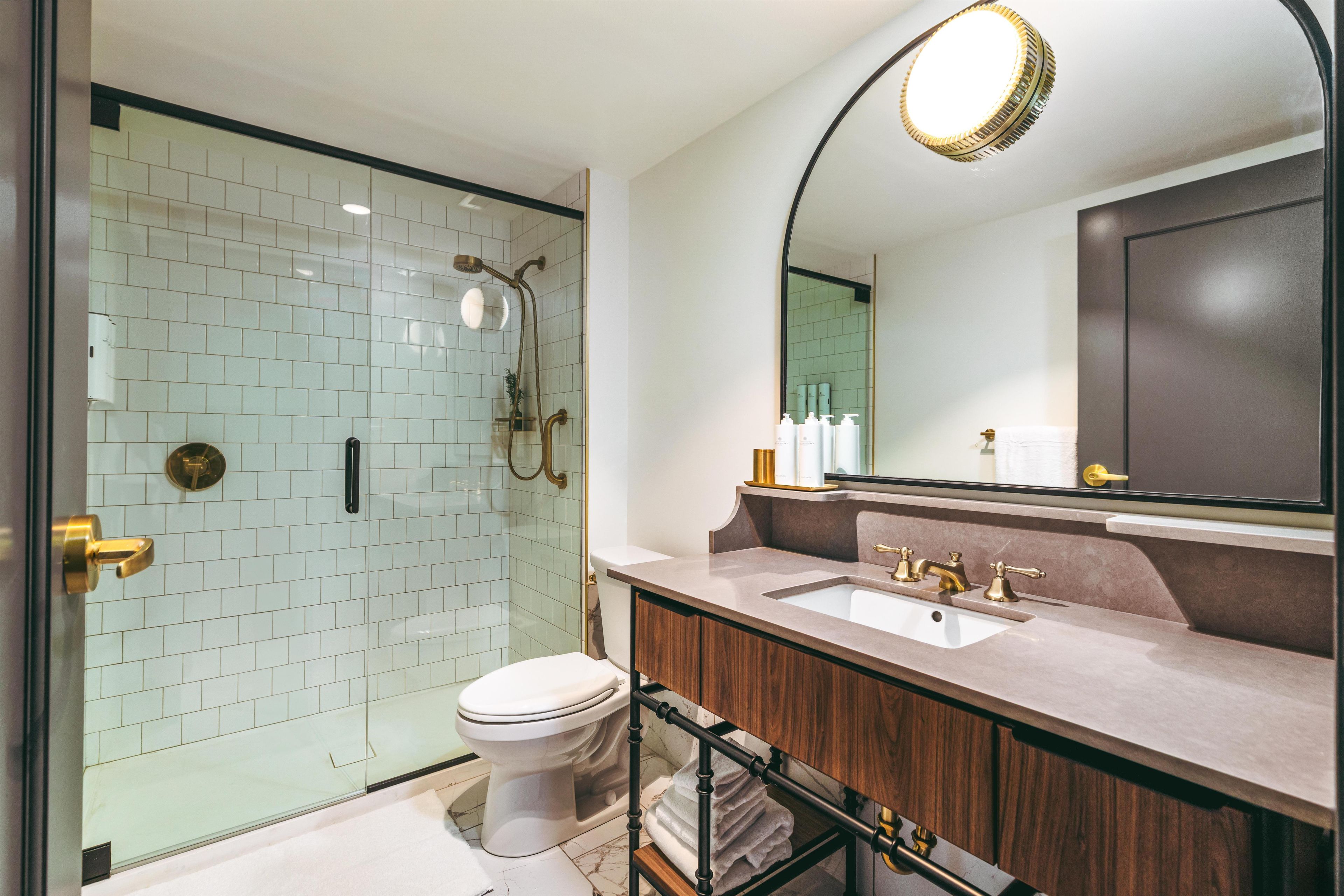 A modern bathroom with a glass-enclosed shower, a toilet, and a vanity with a sink and mirror.