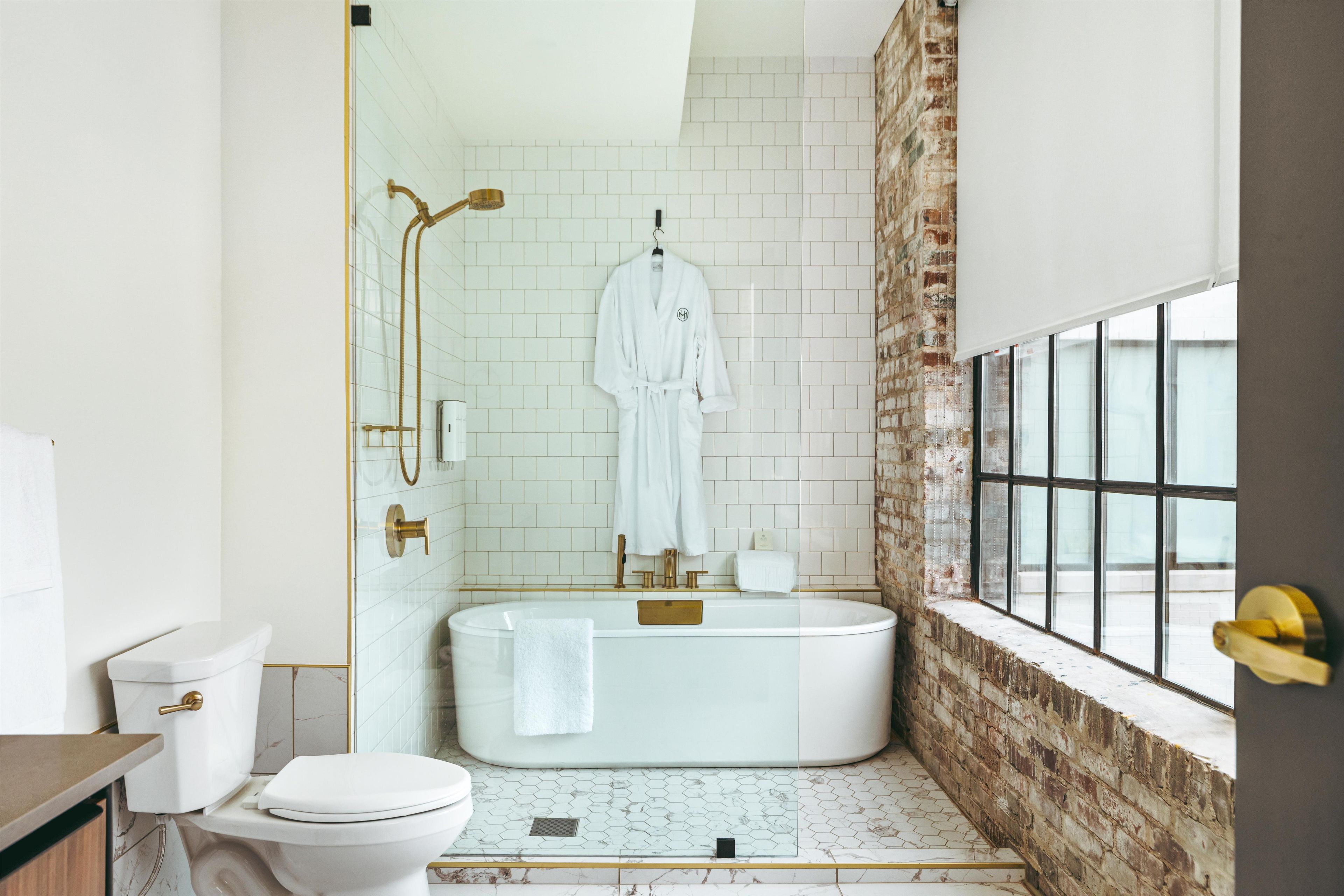 A modern bathroom with a freestanding bathtub, a glass shower enclosure, and a visible window.