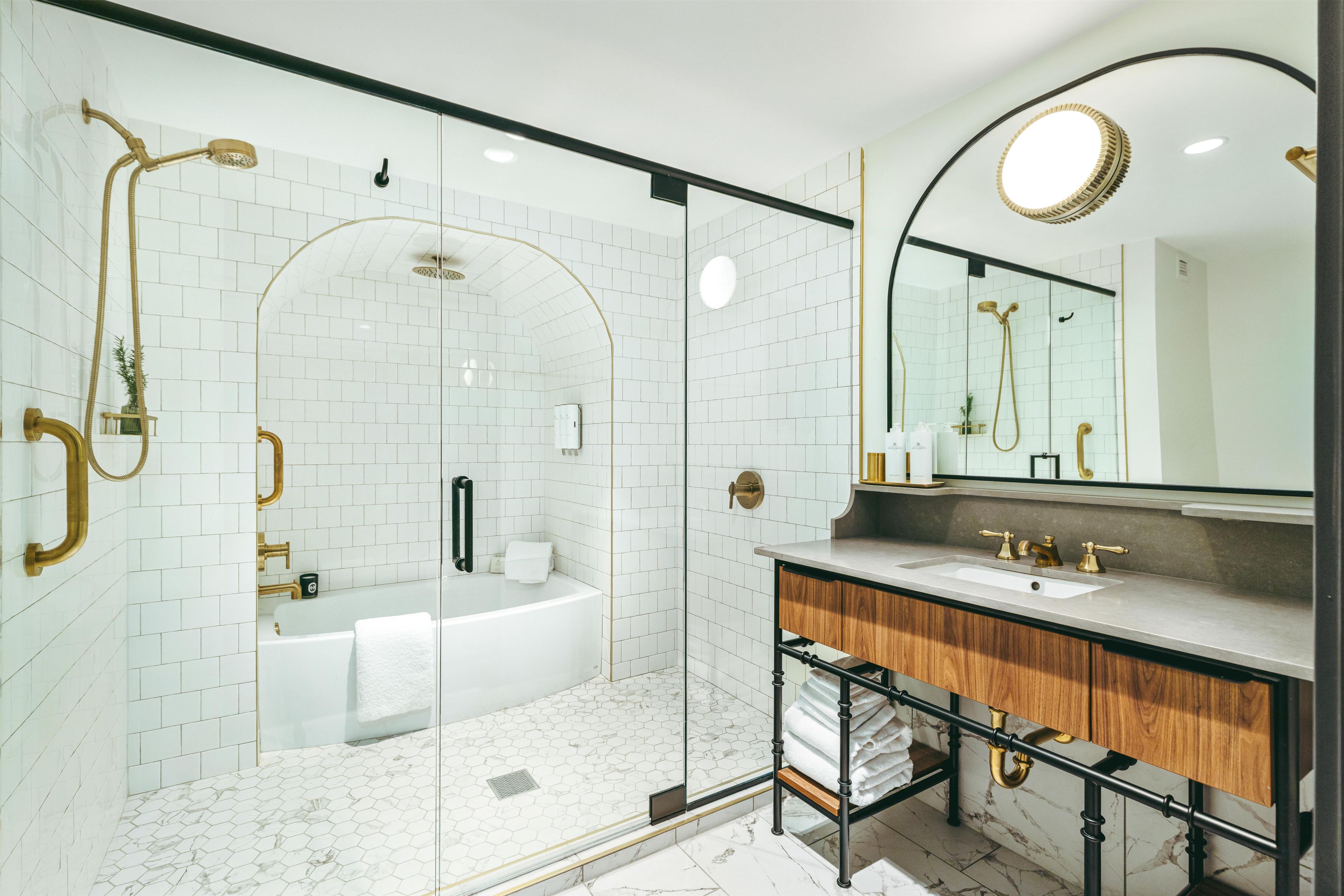A modern bathroom with a glass-enclosed shower, a freestanding bathtub, and a vanity with a marble countertop.