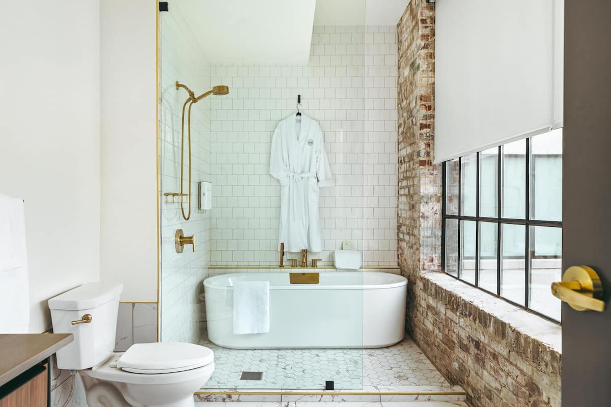 Un baño moderno con una bañera independiente, un inodoro y una ventana con vistas.