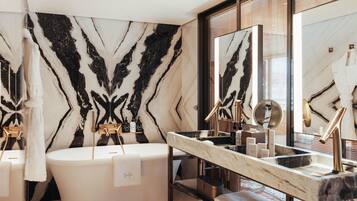 A modern bathroom with a freestanding bathtub, a large mirror, and a marble wall.