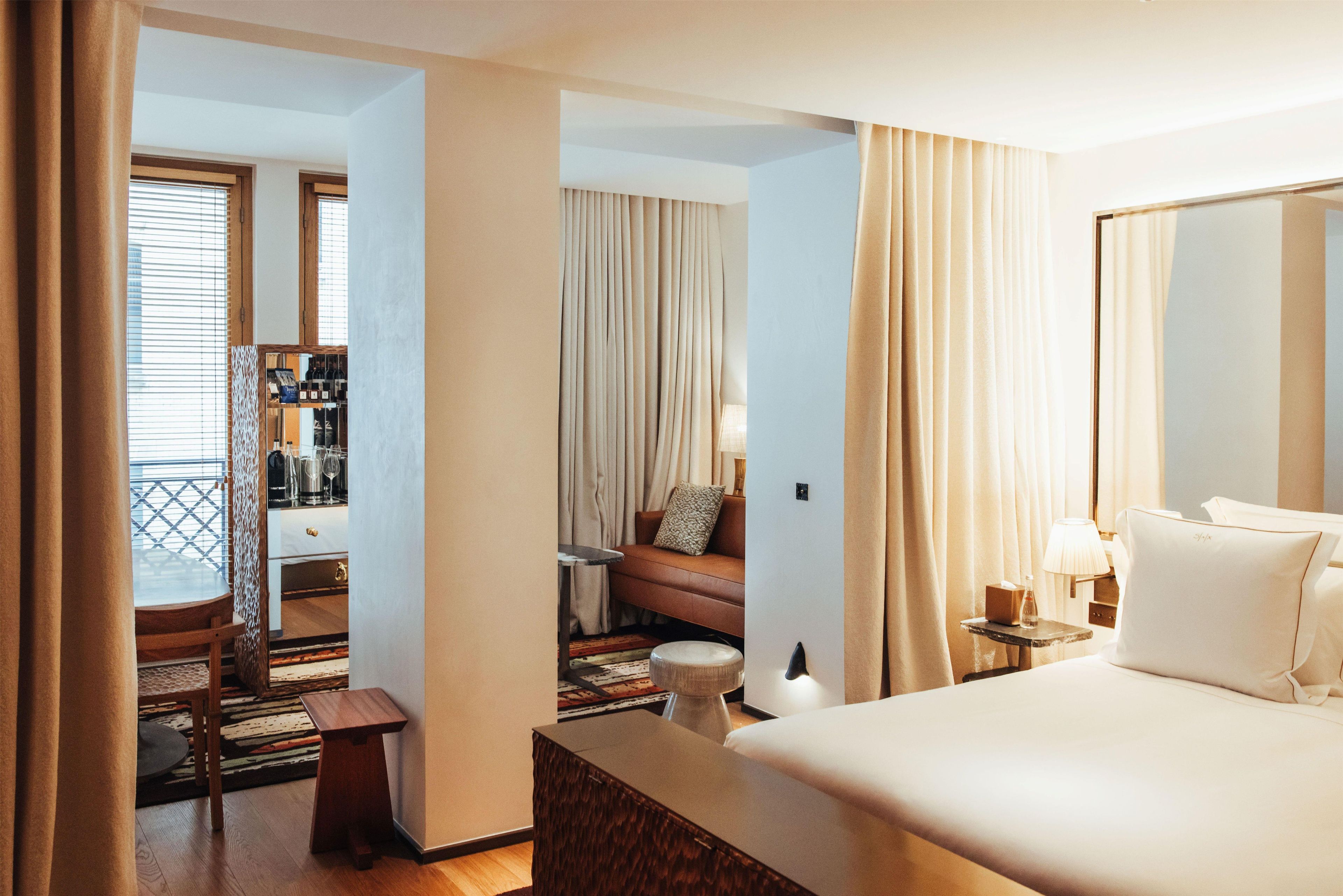 Une chambre d’hôtel avec un lit, une petite table, une table de chevet, une lampe et une vue sur l’extérieur par la fenêtre.