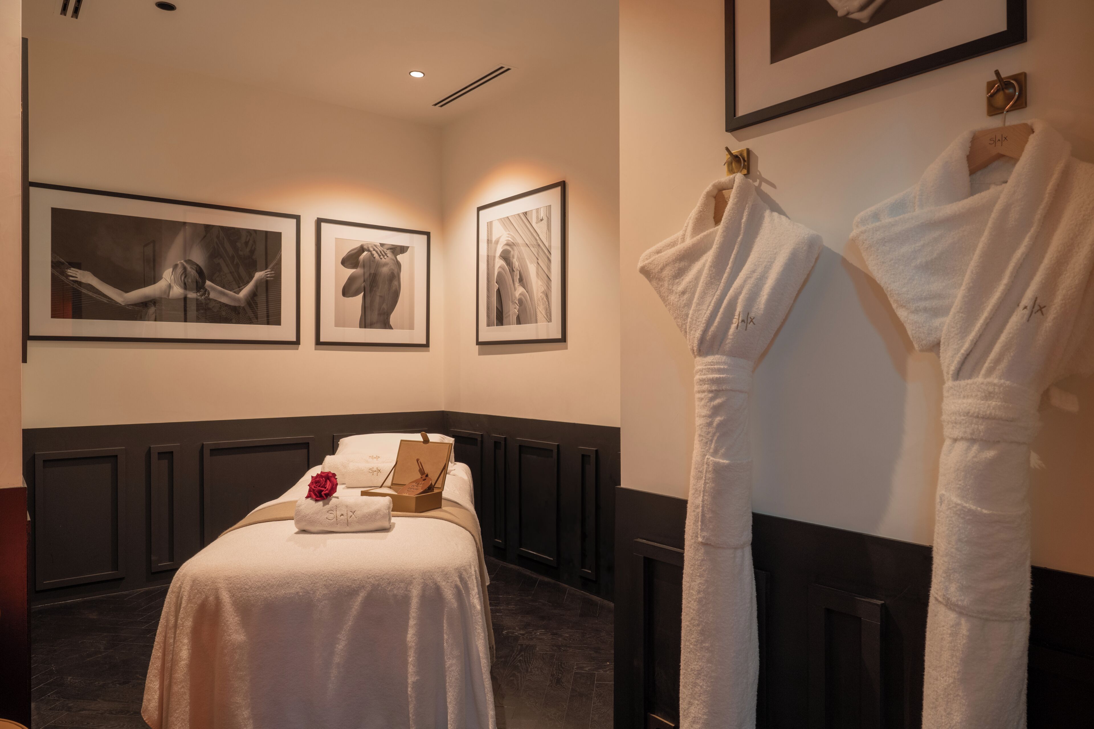 A hotel room with a bed, framed artwork on the wall, and a robe hanging on a rack.