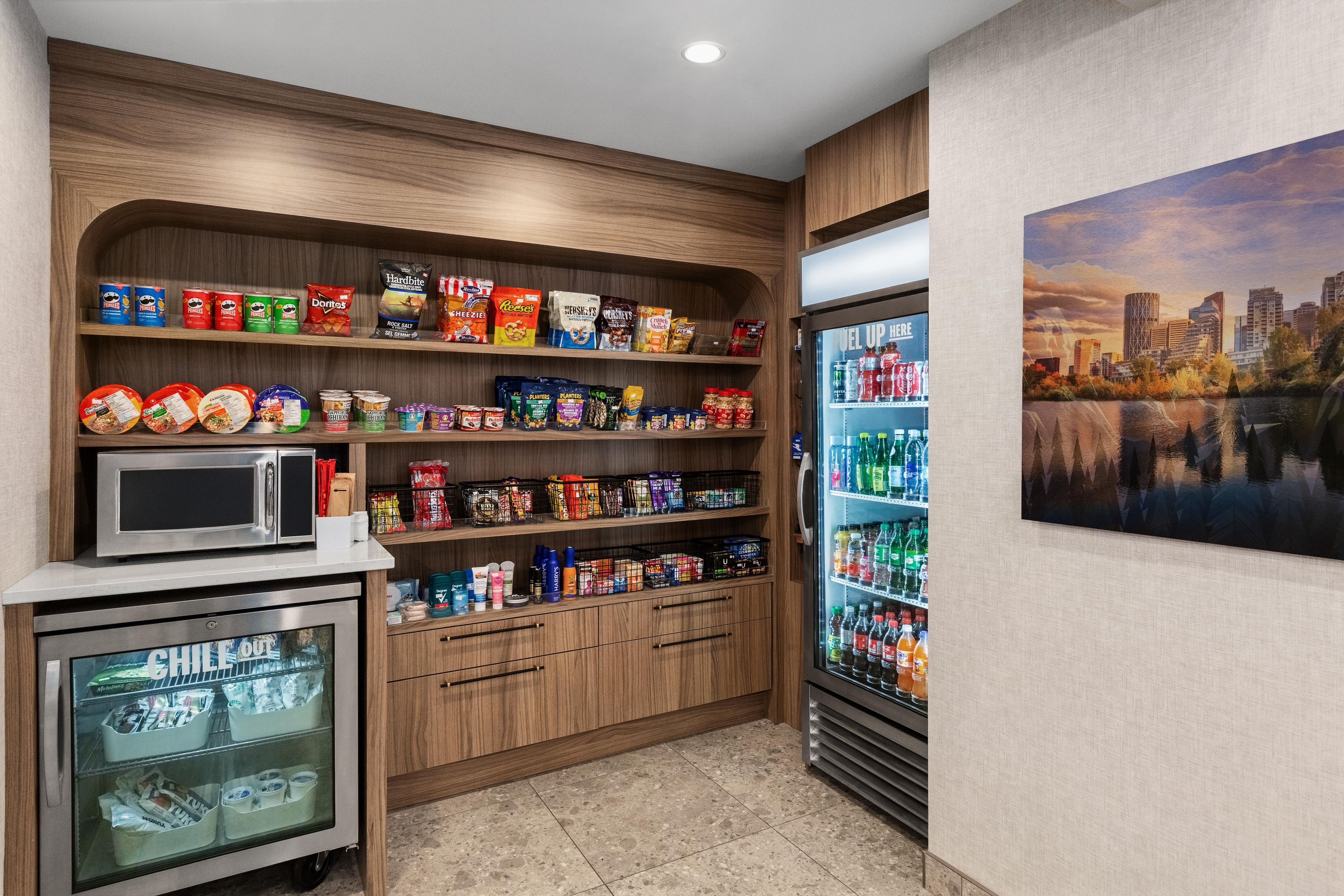 Un área de kitchenette con microondas, refrigerador y despensa provista de aperitivos y condimentos.