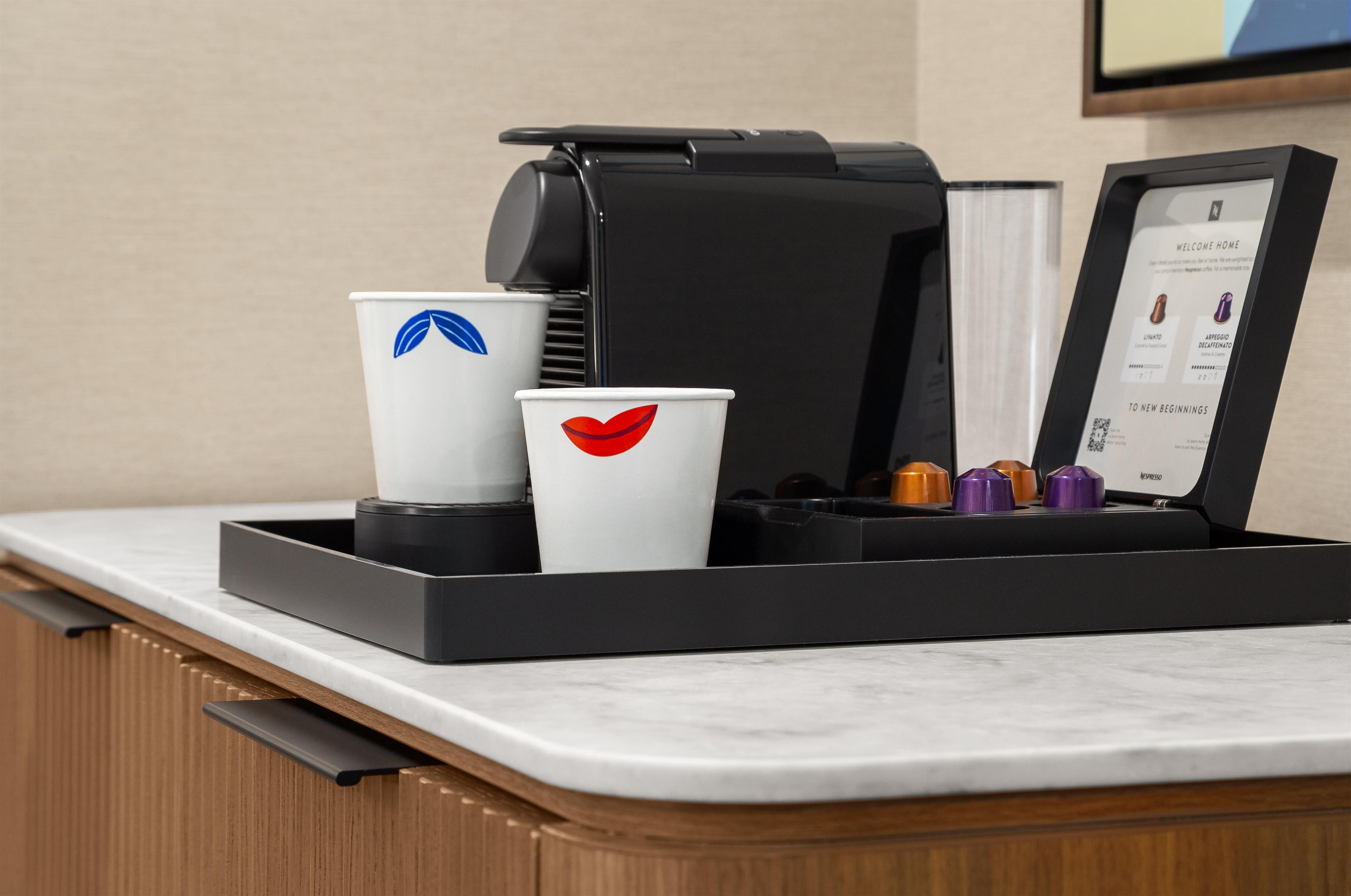 A coffee machine with a digital display and a tray with disposable cups.
