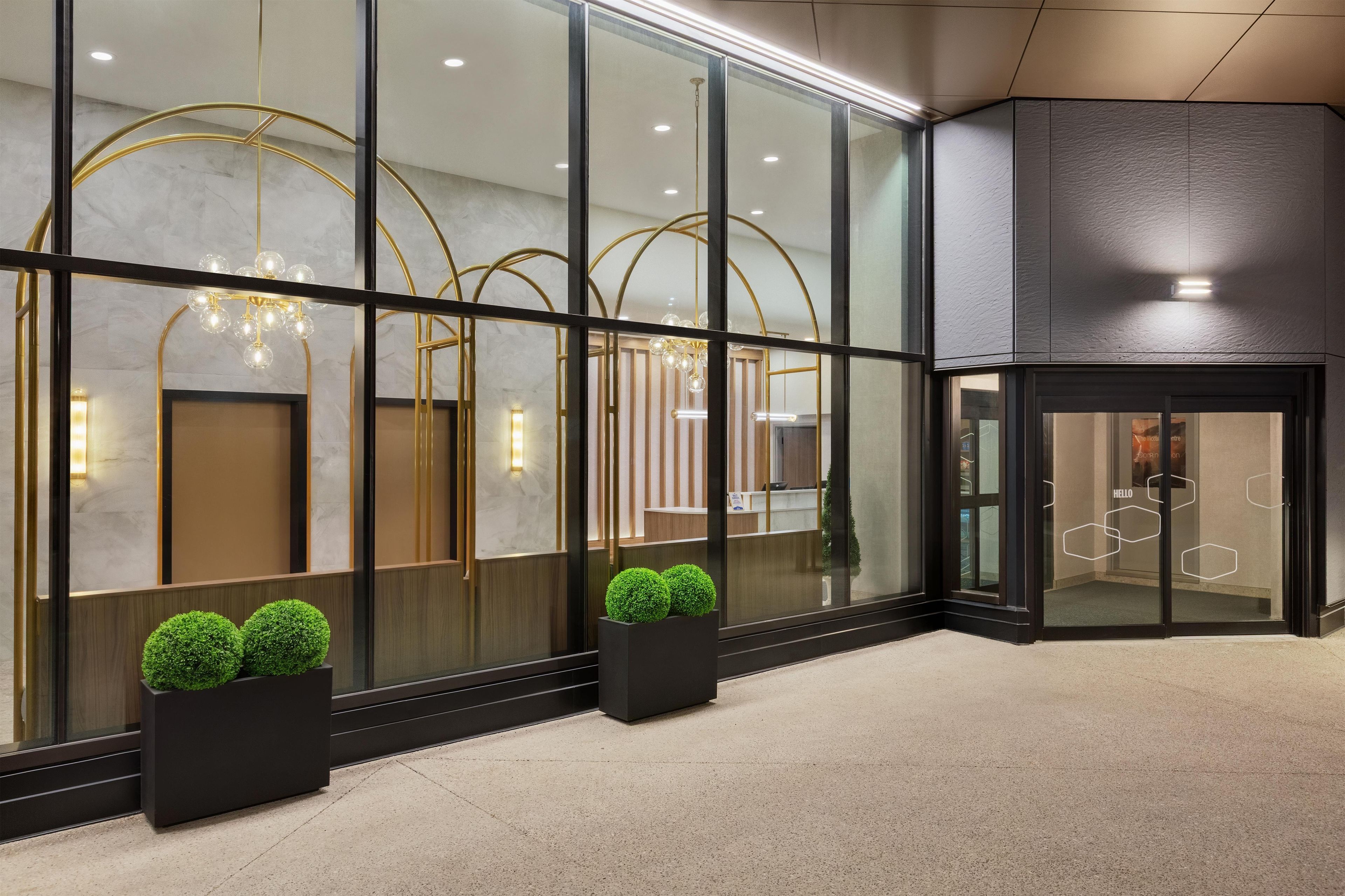 Un moderno vestíbulo de hotel con amplias puertas de vidrio, una recepción y una iluminación decorativa.