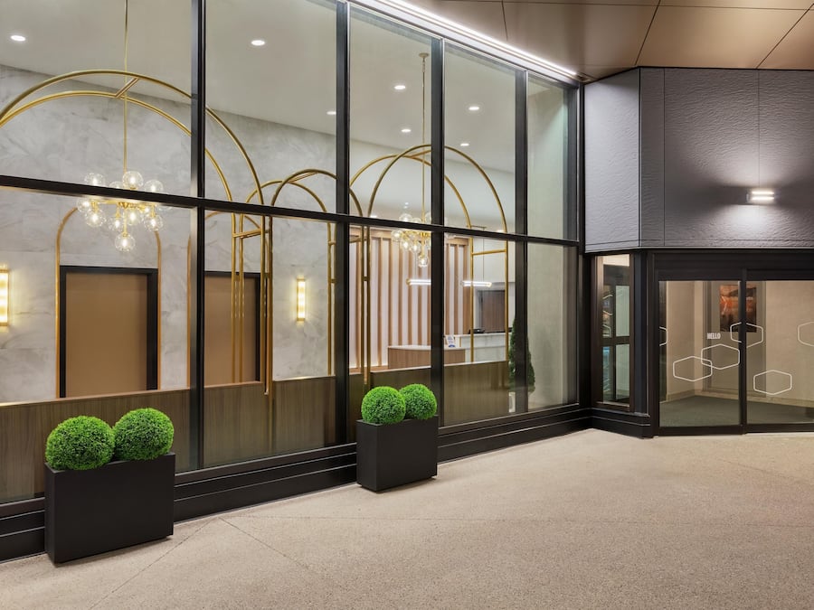 Un moderno vestíbulo de hotel con amplias puertas de vidrio, una recepción y una iluminación decorativa.