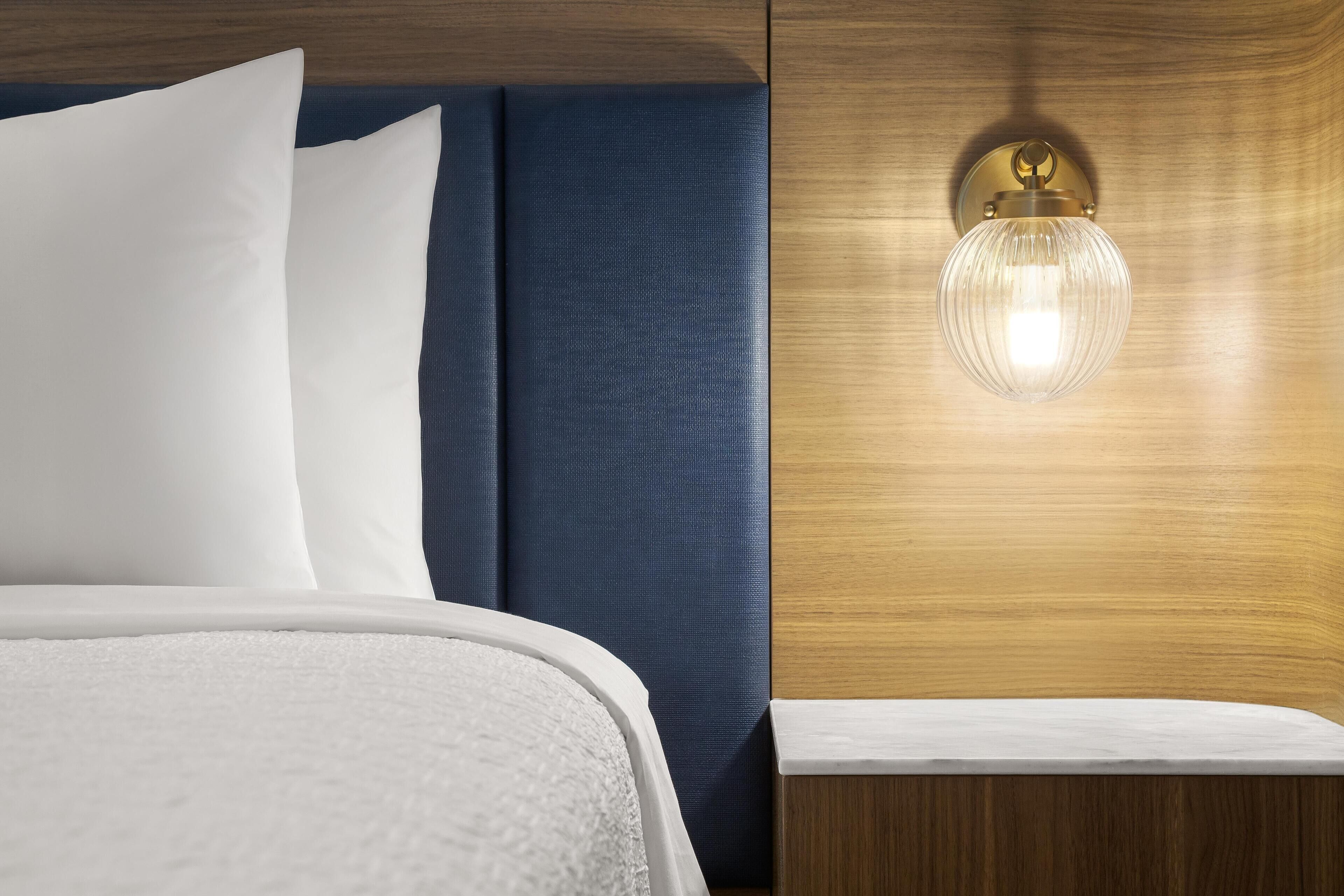 Un lit bien fait, avec du linge de lit blanc et une tête de lit bleue.