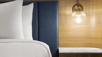 Un lit bien fait, avec du linge de lit blanc et une tête de lit bleue.