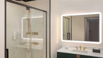 A modern bathroom with a glass-enclosed shower, a white sink with gold fixtures, and a large mirror with integrated lighting.