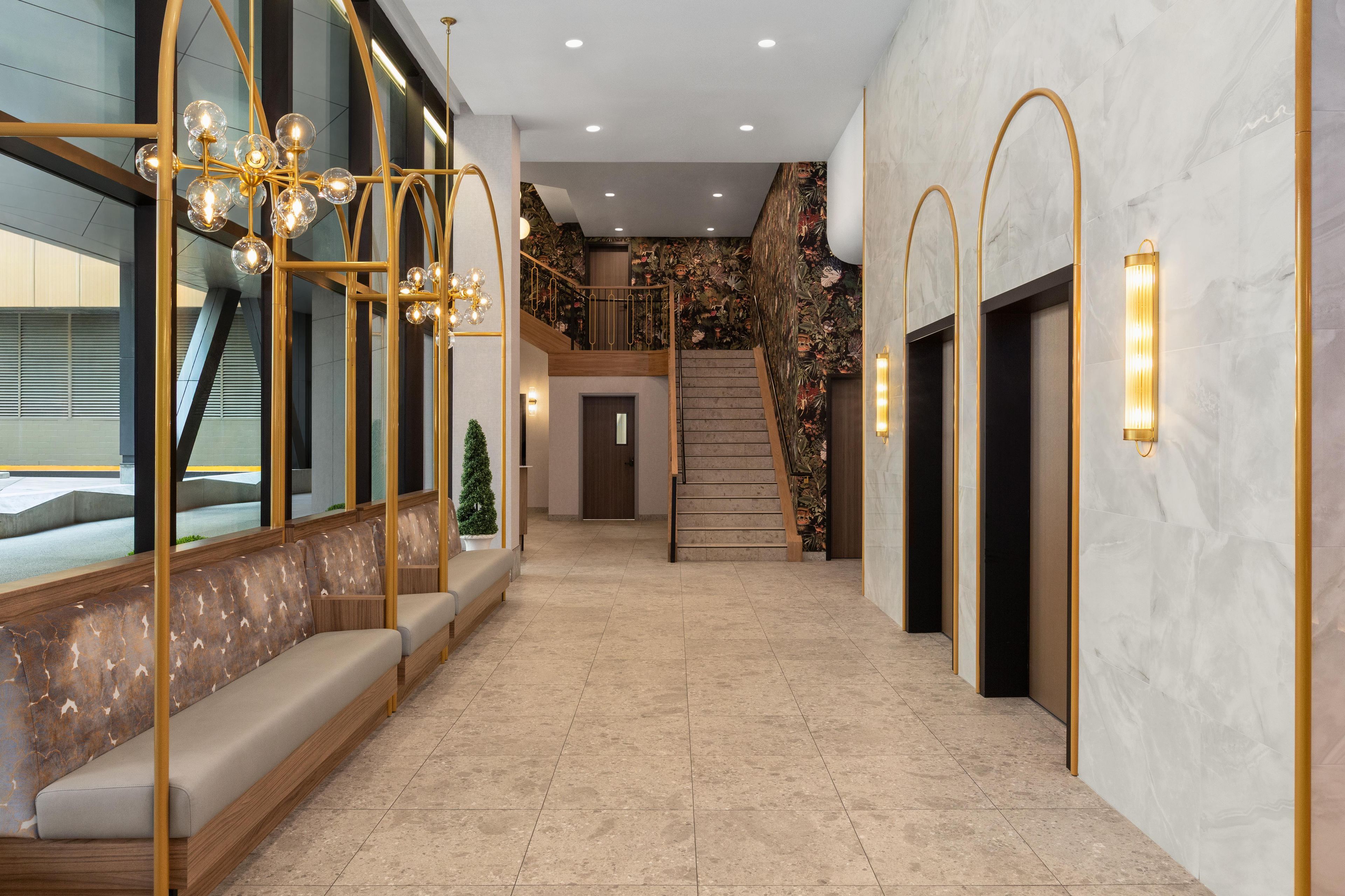 Un interior moderno con una escalera, zona de estar y un muro decorativo.