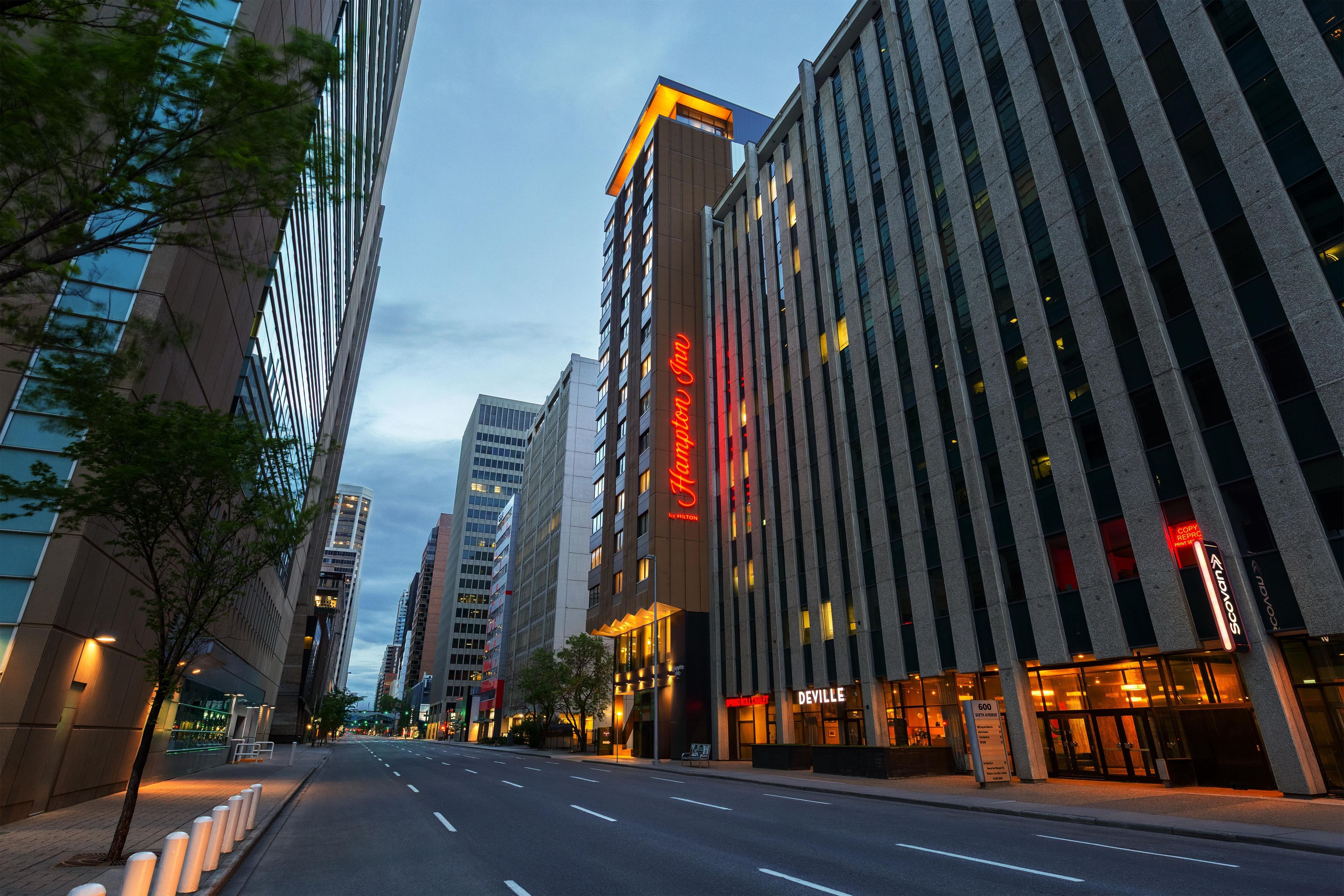 A hotel with a prominent neon sign, a modern facade, and a clear street in front.