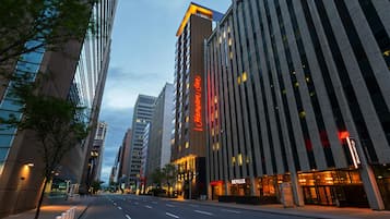 A hotel with a prominent neon sign, a modern facade, and a clear street in front.